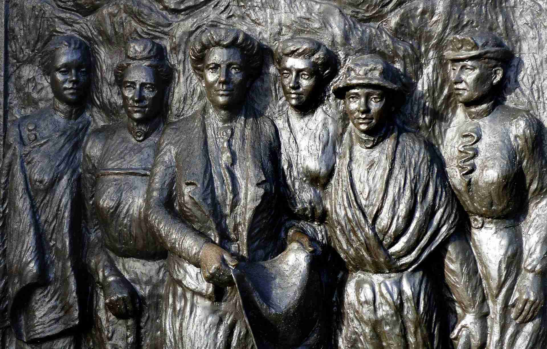 A bronze bas-relief on a stone plinth showing six suffragists walking forward, beside the Avon River in Christchurch.
