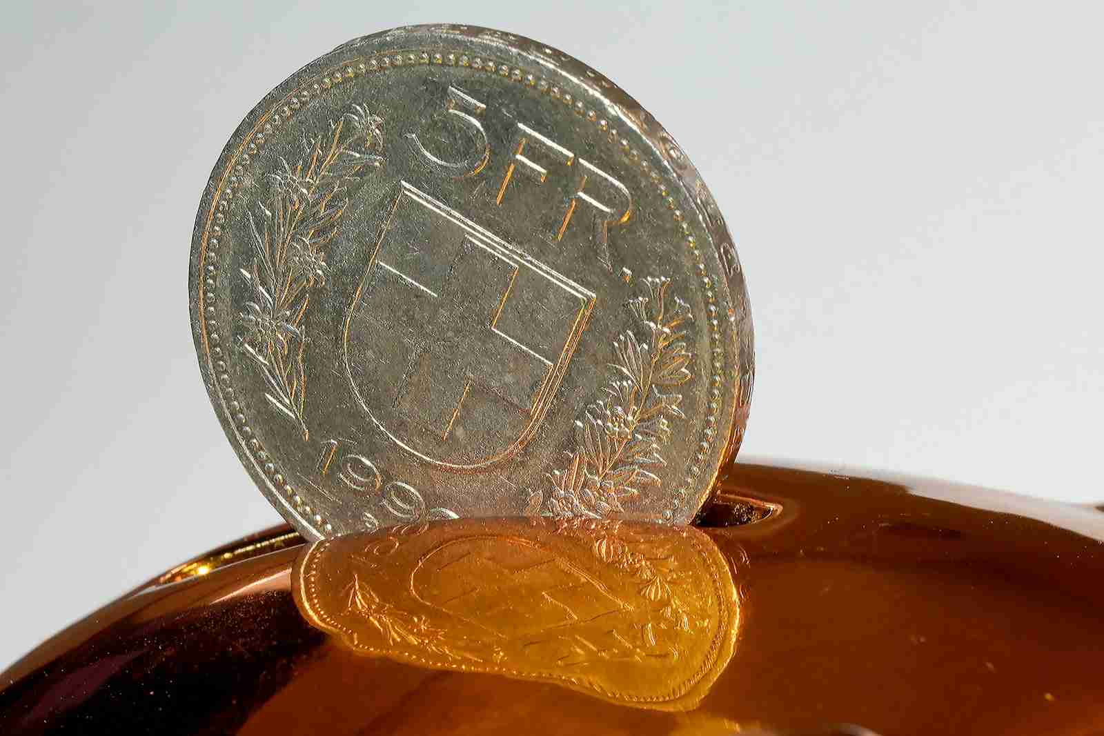 Coin being inserted into a piggy bank — illustrating the missed opportunity to capitalise Kiwibank